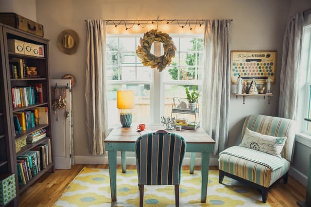 bright beige room with bookcase and eclectic green desk and chairs