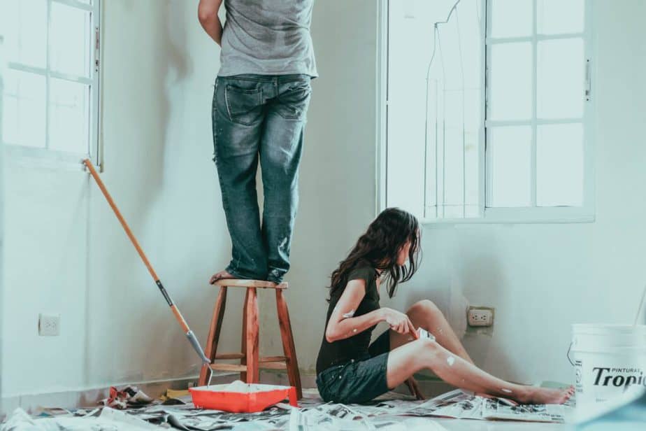 Woman in gray tank top and blue shorts on floor - jeans wearing person standing on stool | Home Maintenance Chores