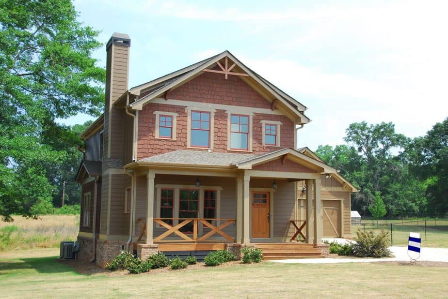 Craftsman inspired new home tan siding natural wood porch and brick red shake siding on upper story