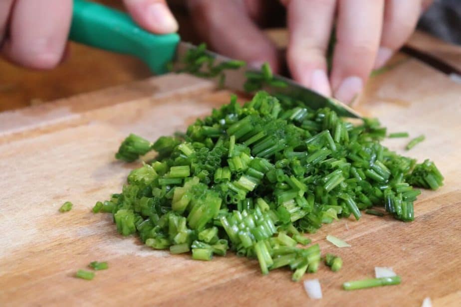 Woman chopping chives on cutting board