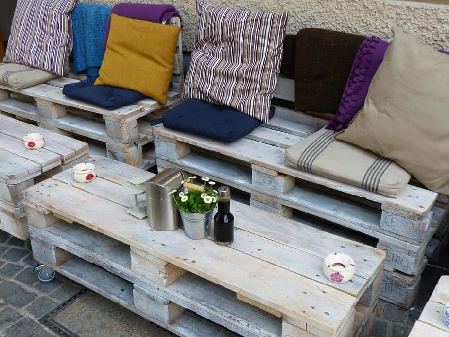 benches made of wooden pallets with mismatched pillows and tales made of pallets sitting in front of them