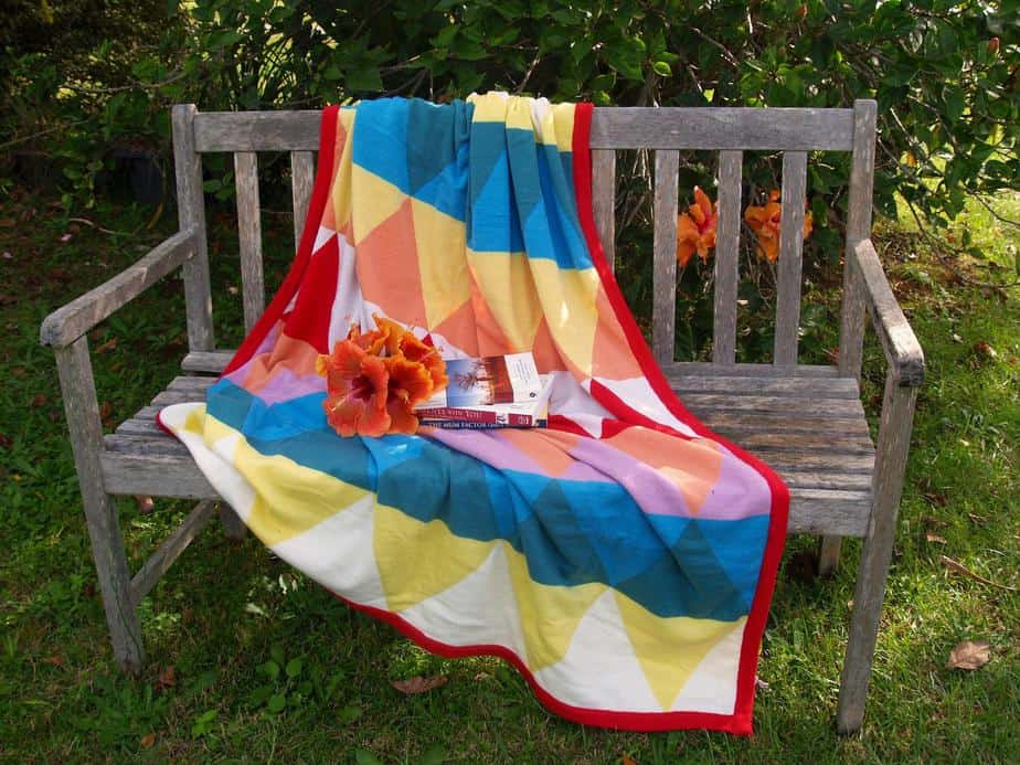 weathered bench with bright blanket and books