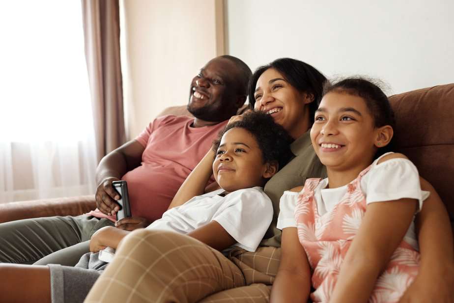 Man, woman, and two children sitting on sofa together in a relaxed and happy way