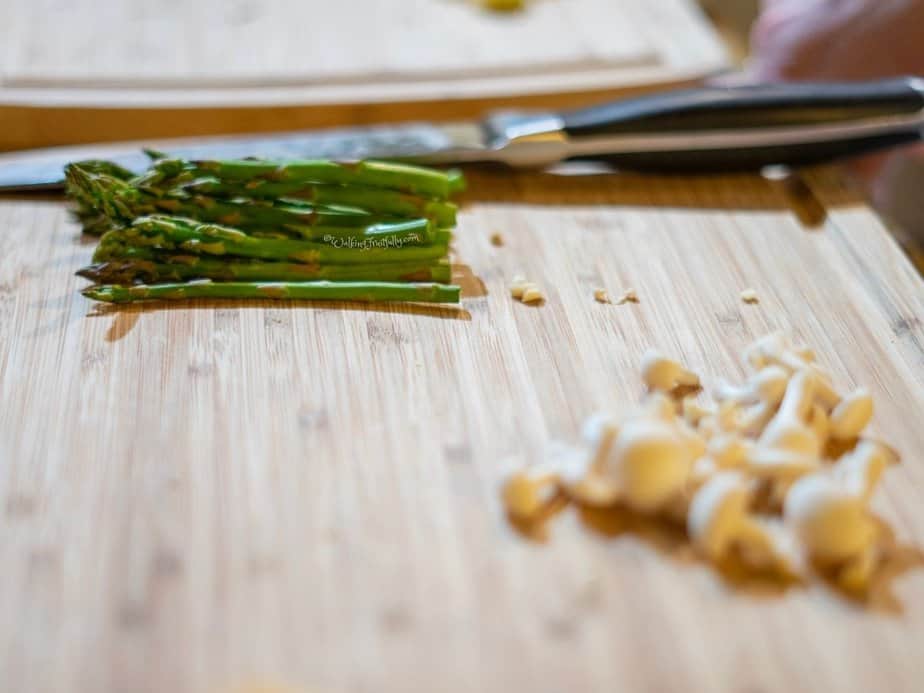 Cutting board with knife and asparagus in focus and mushrooms blurred in foreground