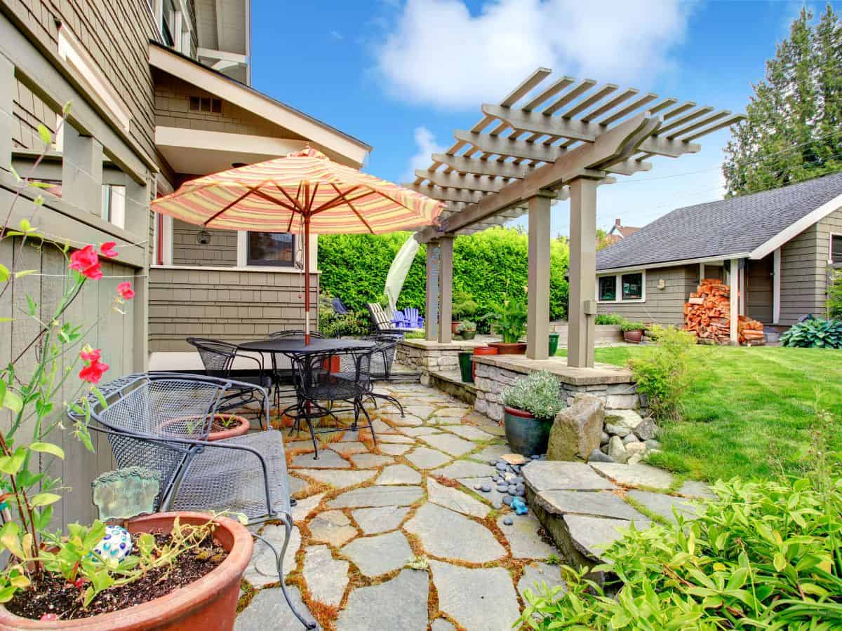 Bright open patio with natural stone paving, umbrella over table and seating