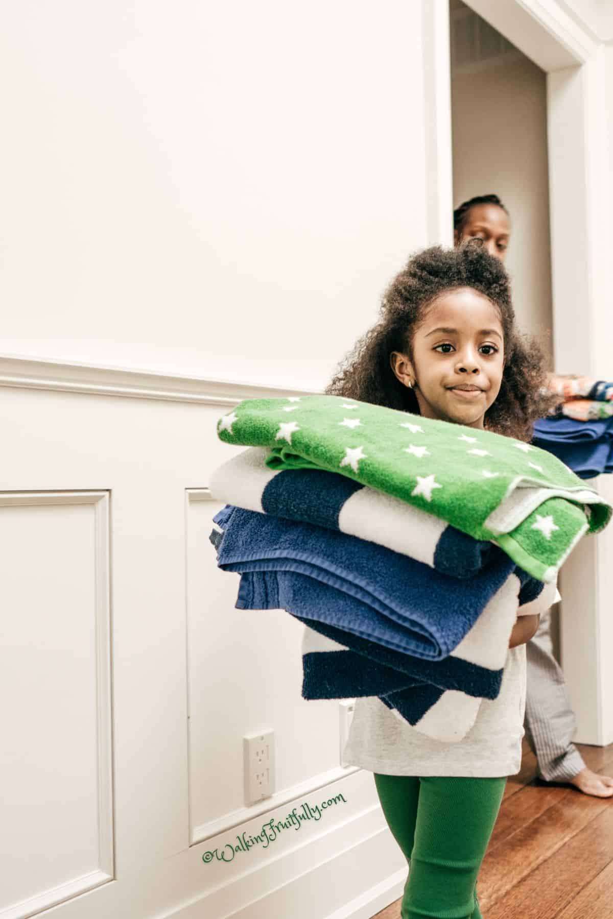 Child helping carry folded towels