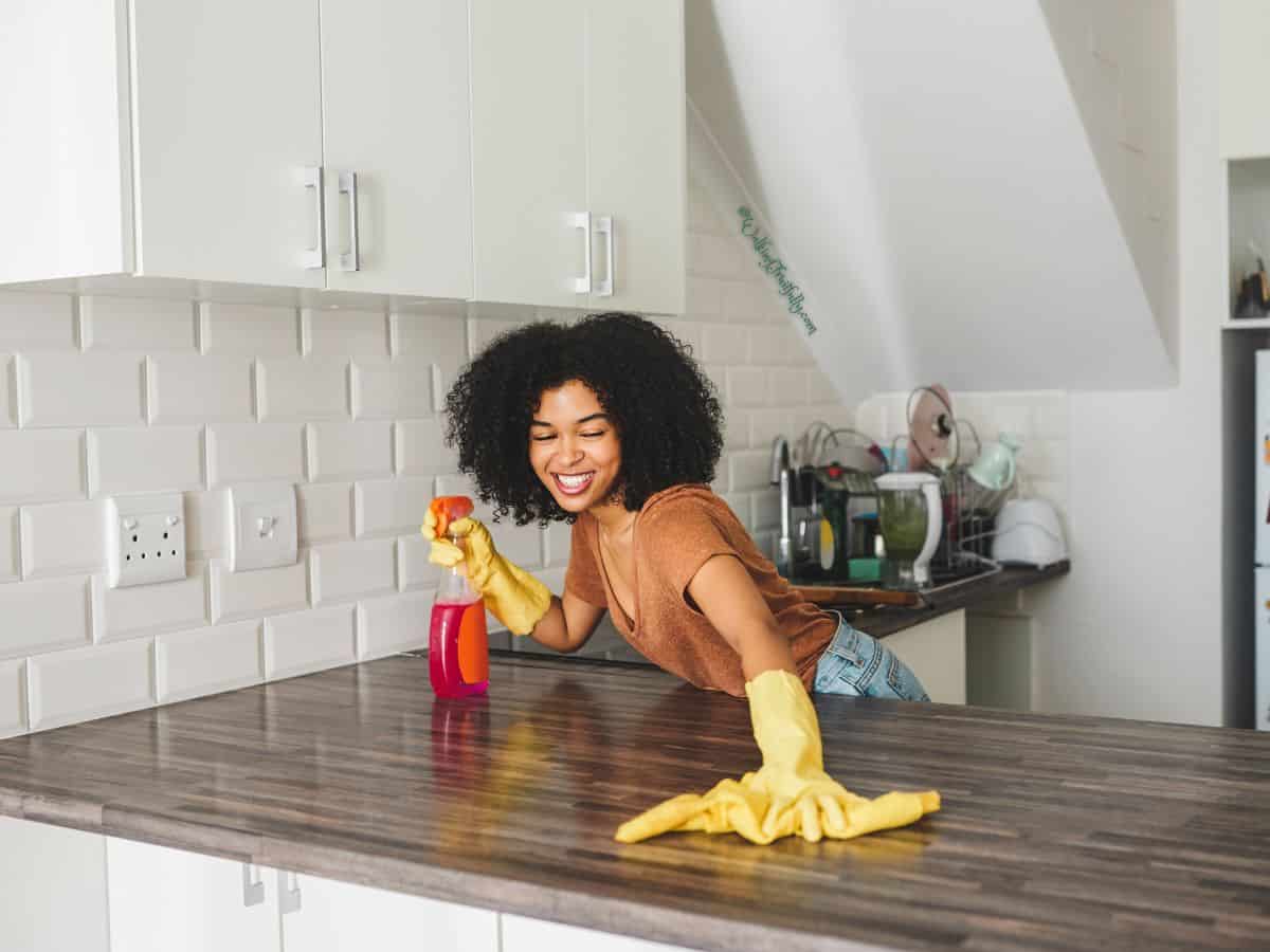 Young woman wearing gloves cleaning her home.