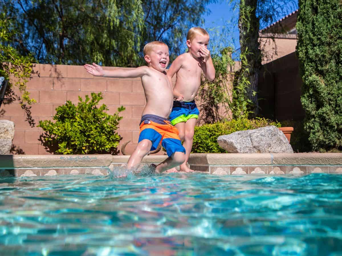 Twin boys having fun in backyard pool
