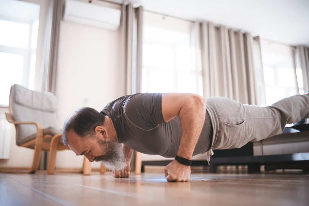 Older man wearing grey t-shirt and joggers doing pushups